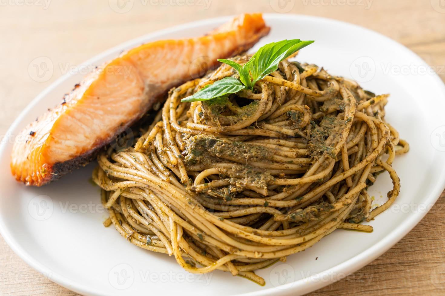 spaghetti al pesto fatti in casa con salmone alla griglia - stile italiano foto