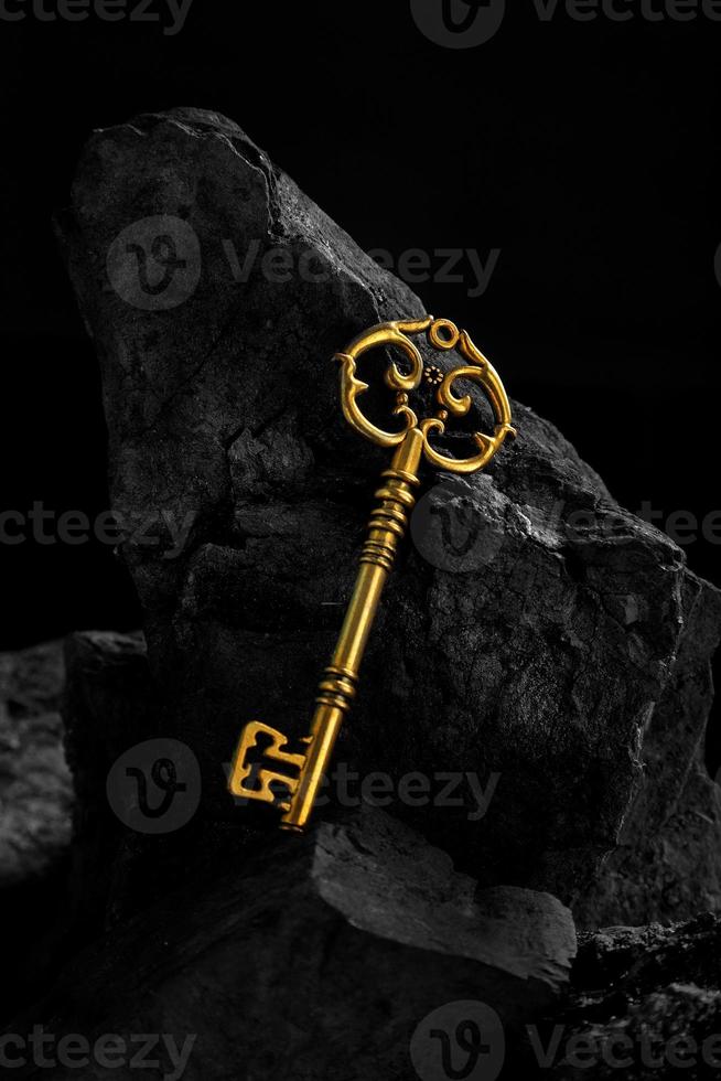 chiave d'oro antica su sfondo di superficie in pietra di carbone scuro foto