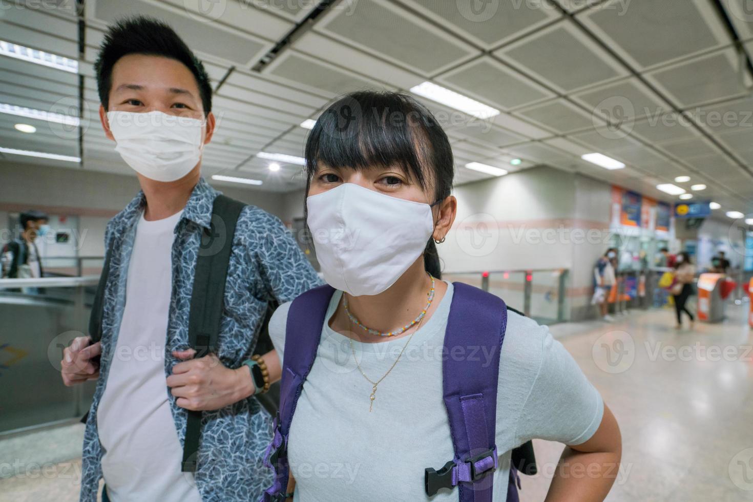 coppia asiatica che indossa una maschera sanitaria per viaggiare in metropolitana in thailandia foto