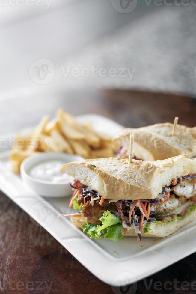 panino di filetto di pesce fresco fritto in pastella con insalata di cavolo cappuccio patatine fritte e salsa tartara foto