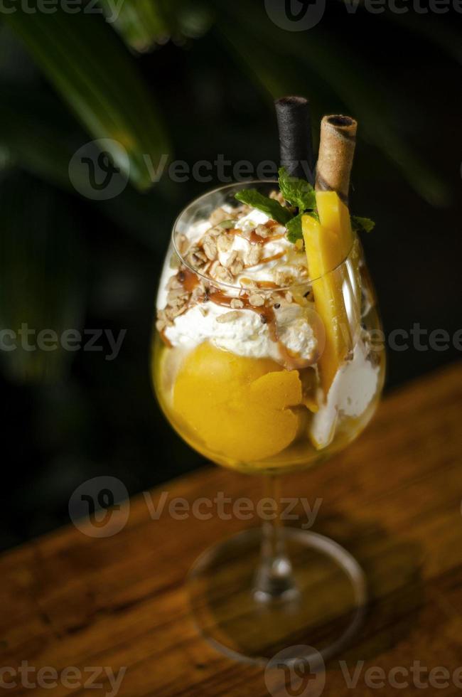 Coppa di gelato tropicale al mango biologico e frutto della passione nel bicchiere da vino foto