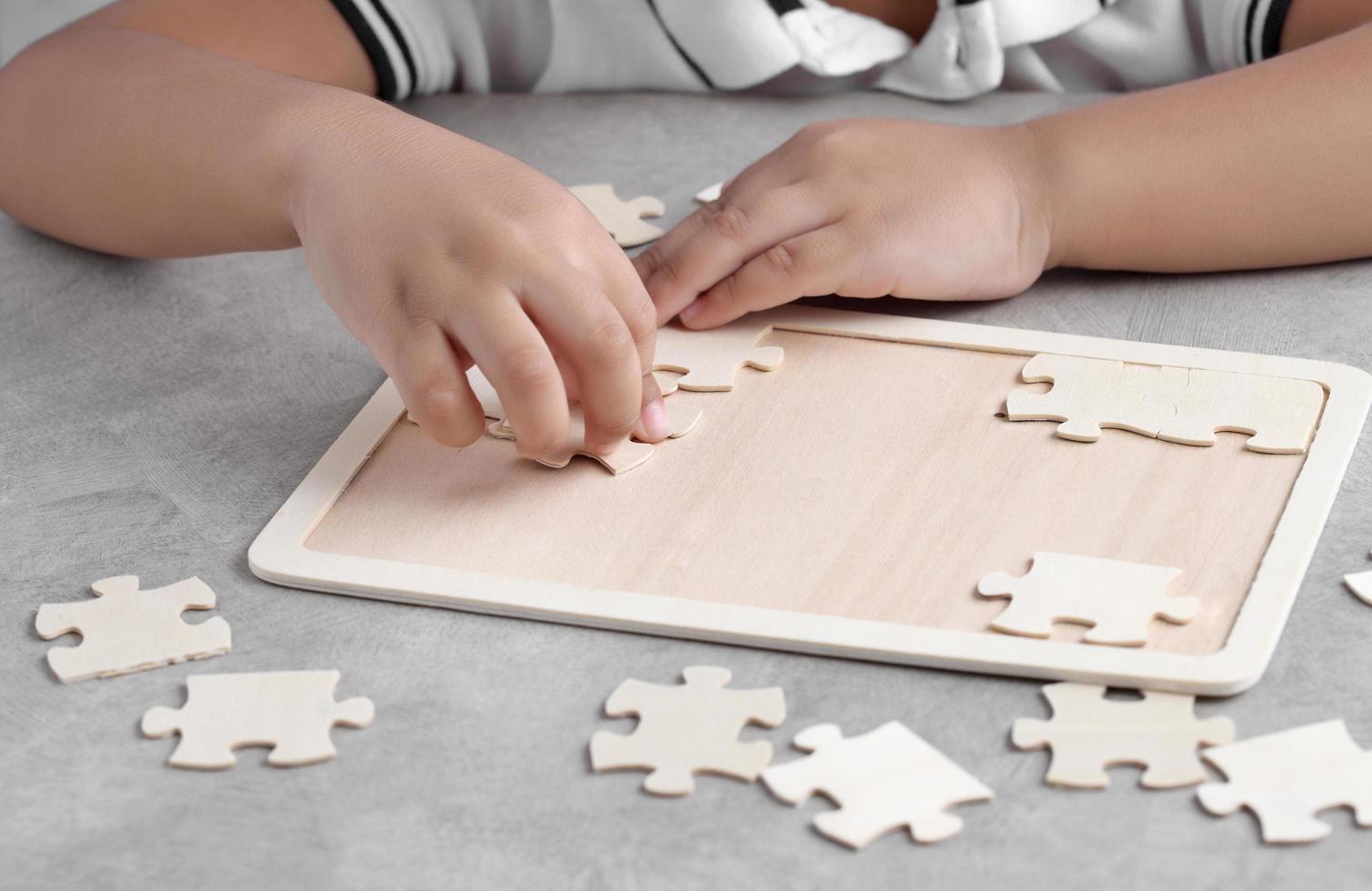 ragazzino asiatico che gioca a puzzle in legno foto