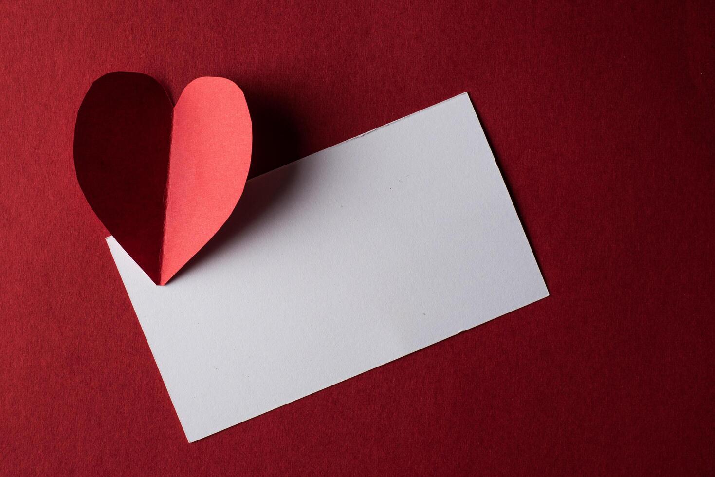 carta cuore rosso e vuoto con carta nota su sfondo rosso. foto
