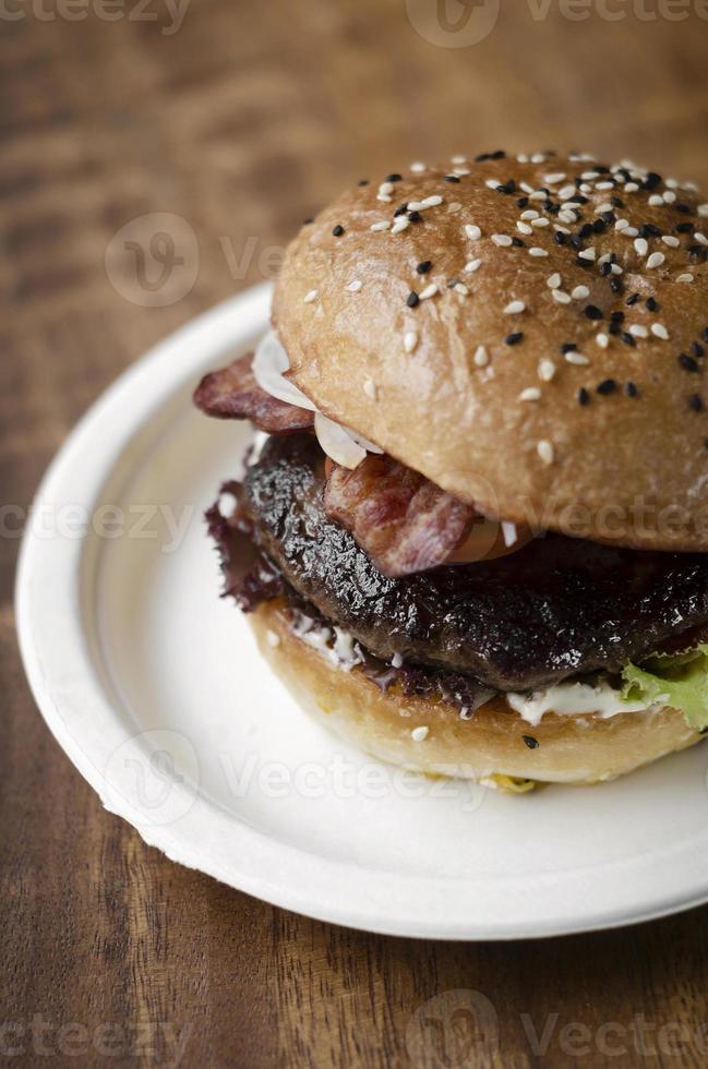 hamburger di manzo biologico australiano con pancetta su sfondo tavolo in legno foto