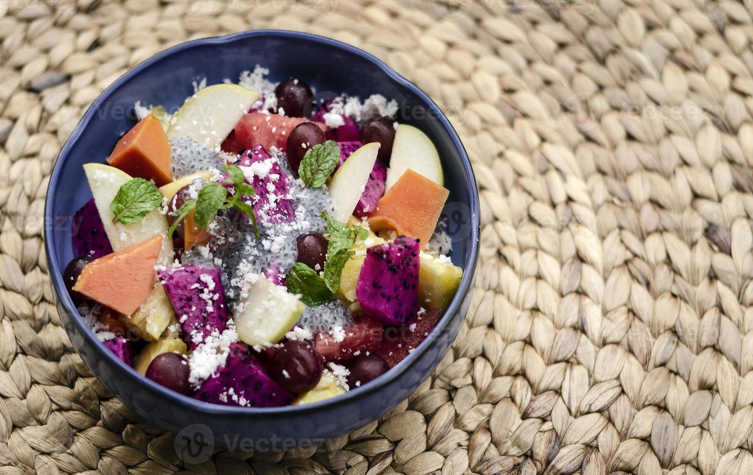 insalata di frutta asiatica tropicale mista esotica con semi di basilico e cocco in una ciotola all'aperto foto