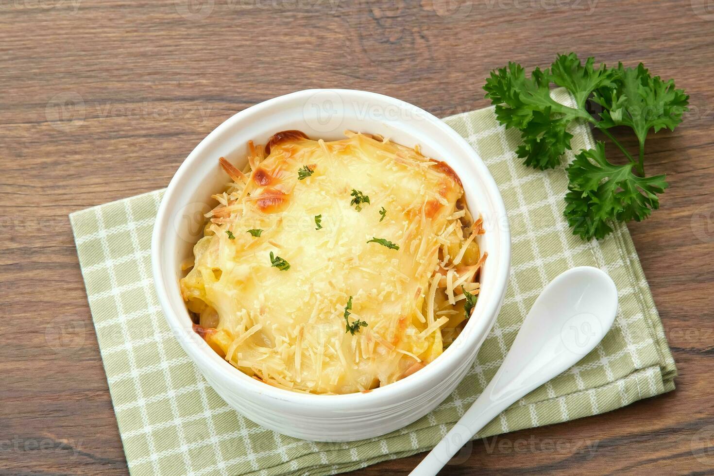 al forno maccheroni e formaggio su un' bianca ciotola con parmigiano e erbe aromatiche foto