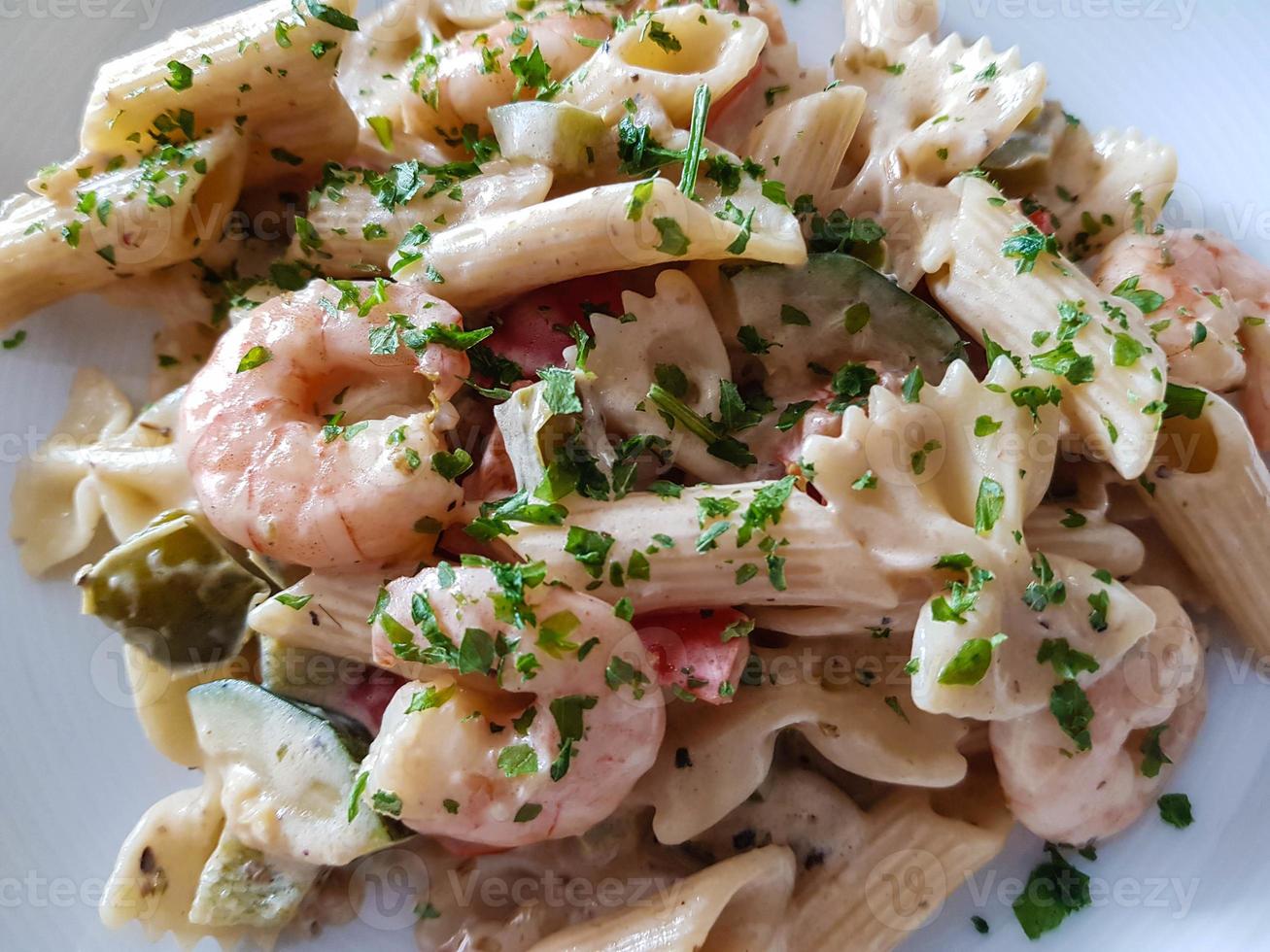 tegame di pasta colorata con verdure e gamberoni bianchi foto