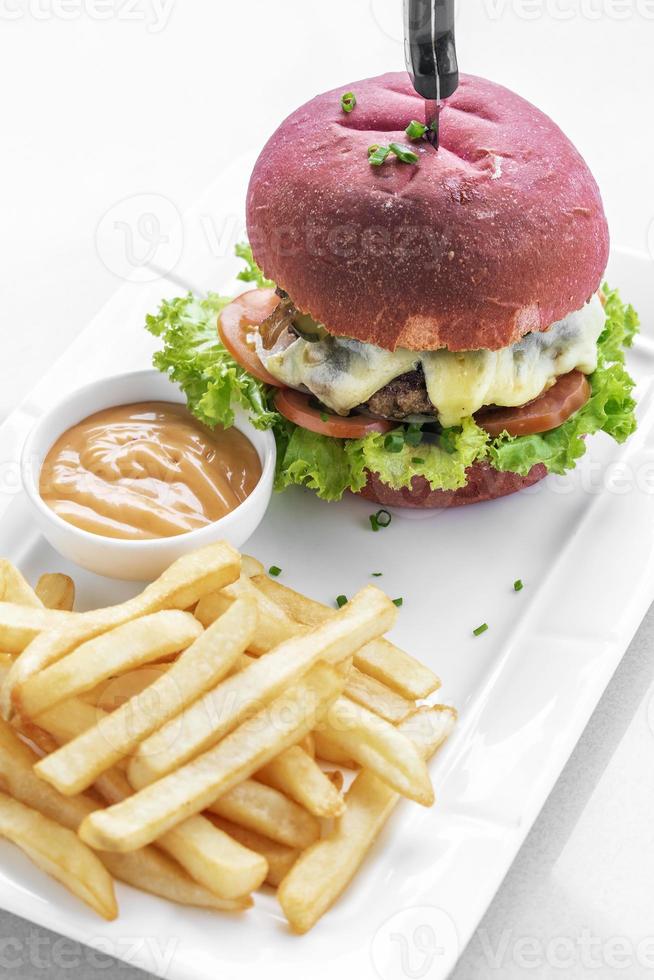 set di snack per hamburger al formaggio con panino rosso di barbabietola con patatine fritte e maionese al peperoncino su piastra bianca foto