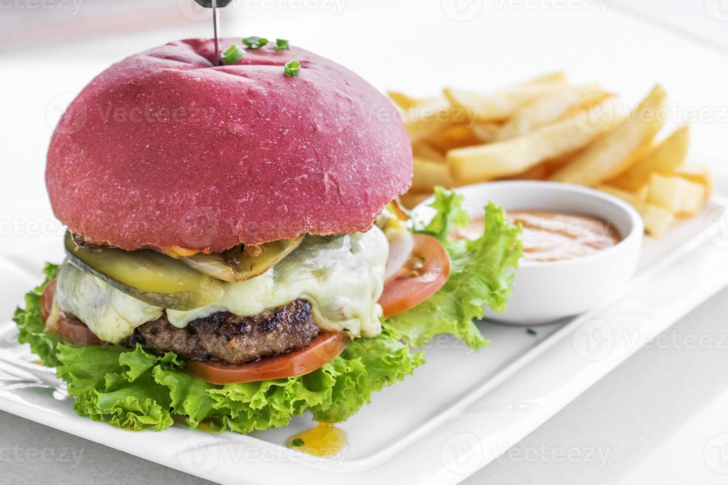 set di snack per hamburger al formaggio con panino rosso di barbabietola con patatine fritte e maionese al peperoncino su piastra bianca foto