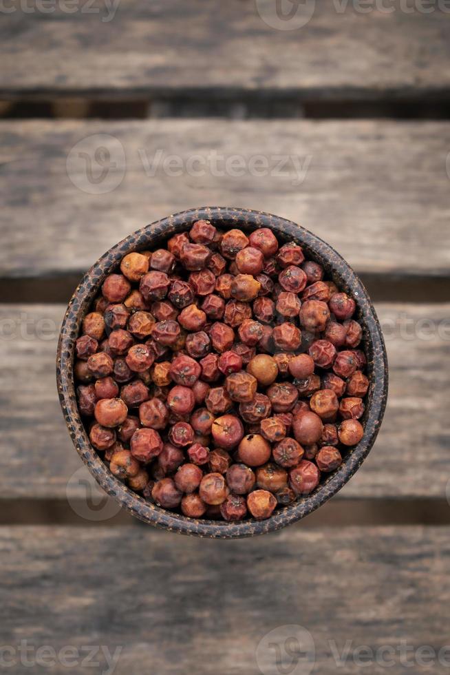 Kampot biologico in grani essiccati di peperone rosso in Cambogia in una tradizionale ciotola di legno asiatico foto