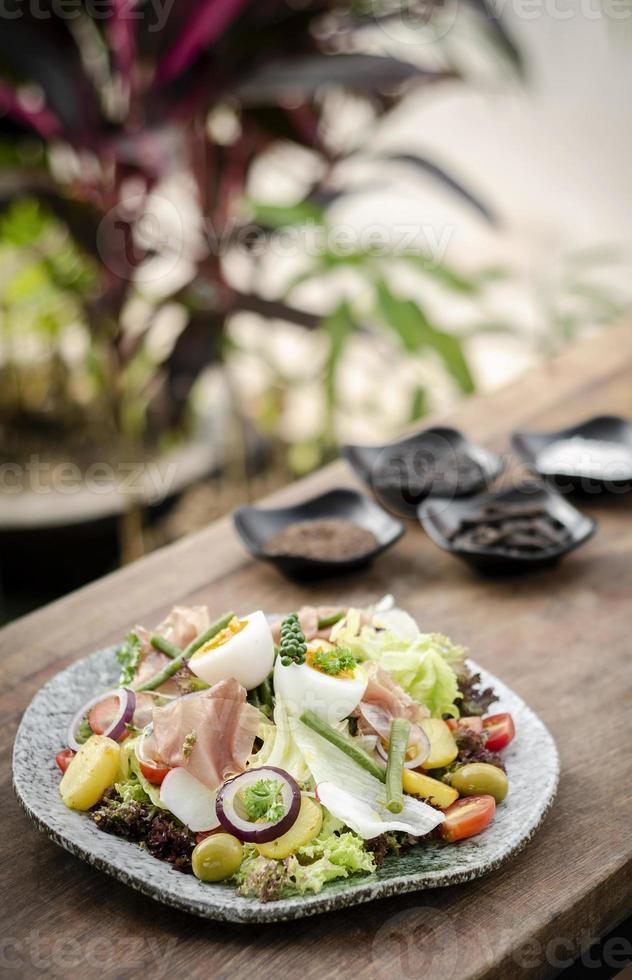 Insalata rustica biologica sana in stile nizzarda con uova e prosciutto all'aperto foto