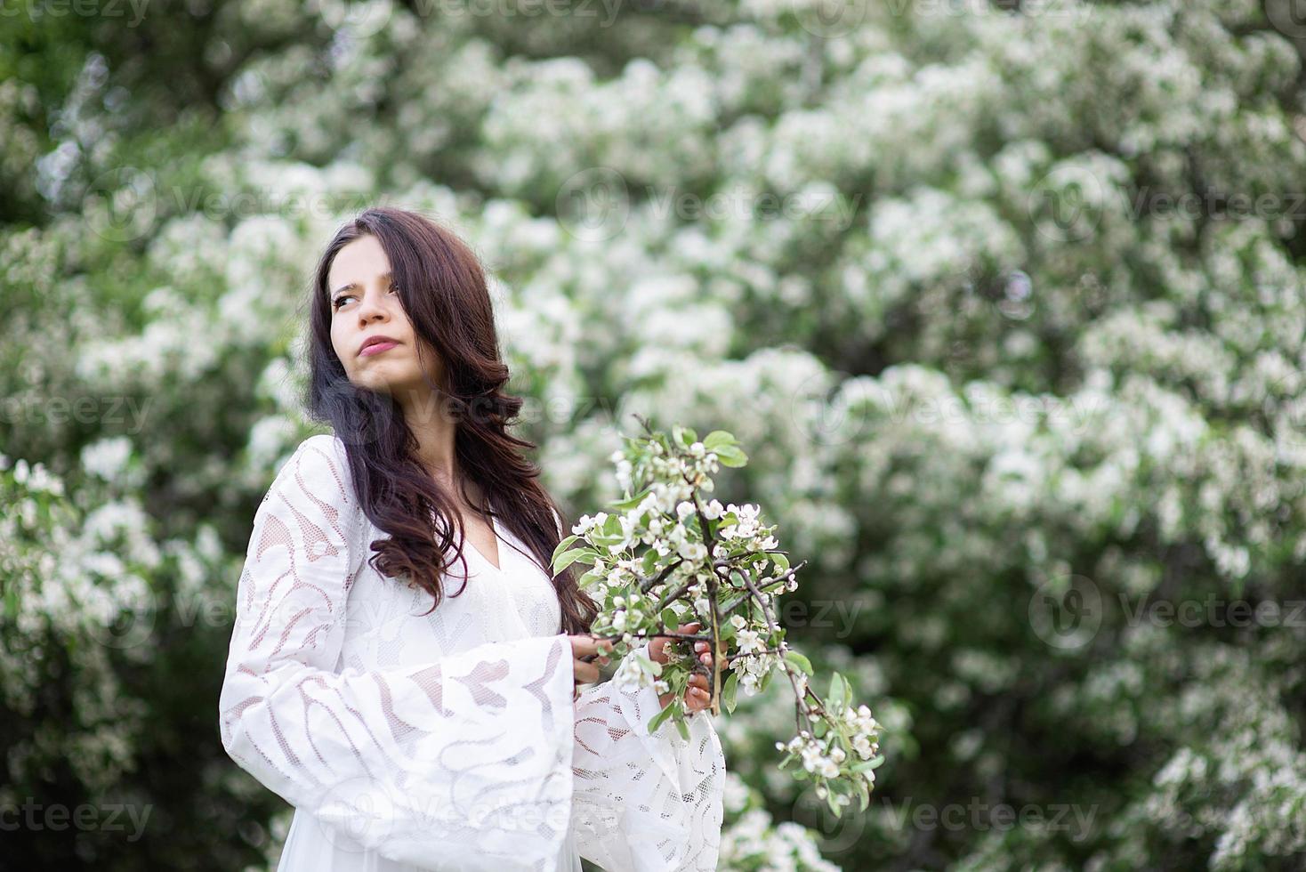 ritratto di una bellissima giovane donna nel parco tra rami fioriti foto