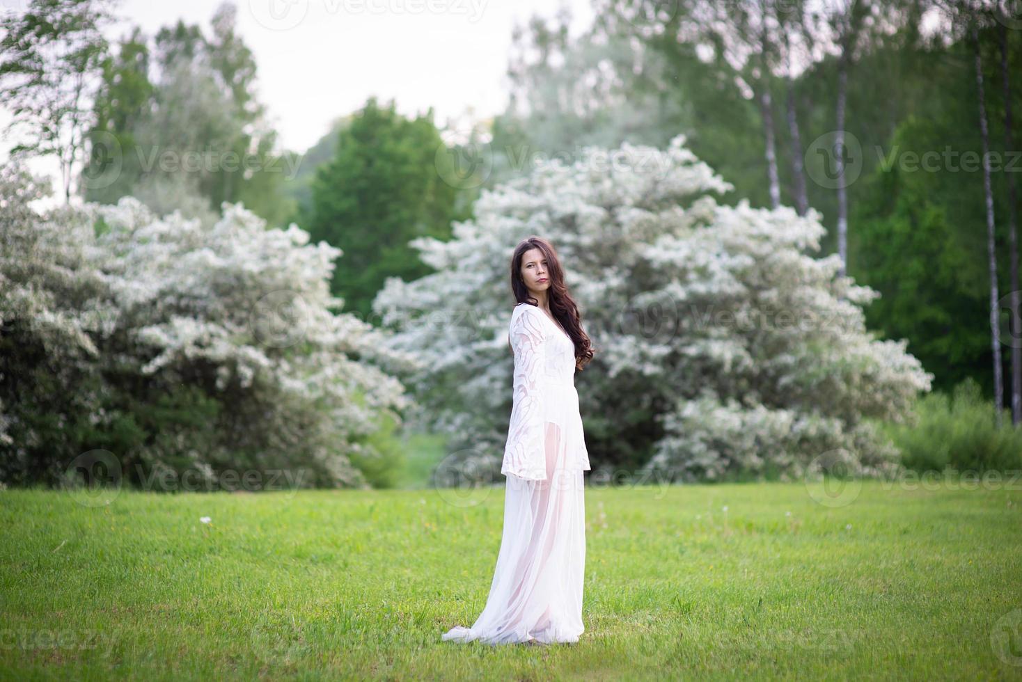 ritratto di una bellissima giovane donna nel parco tra rami fioriti foto