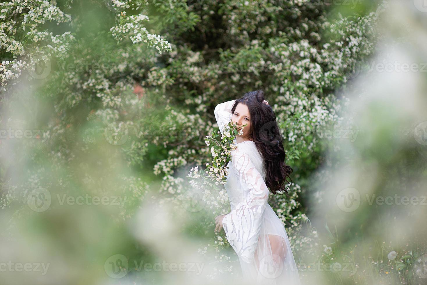 ritratto di una bellissima giovane donna nel parco tra rami fioriti foto