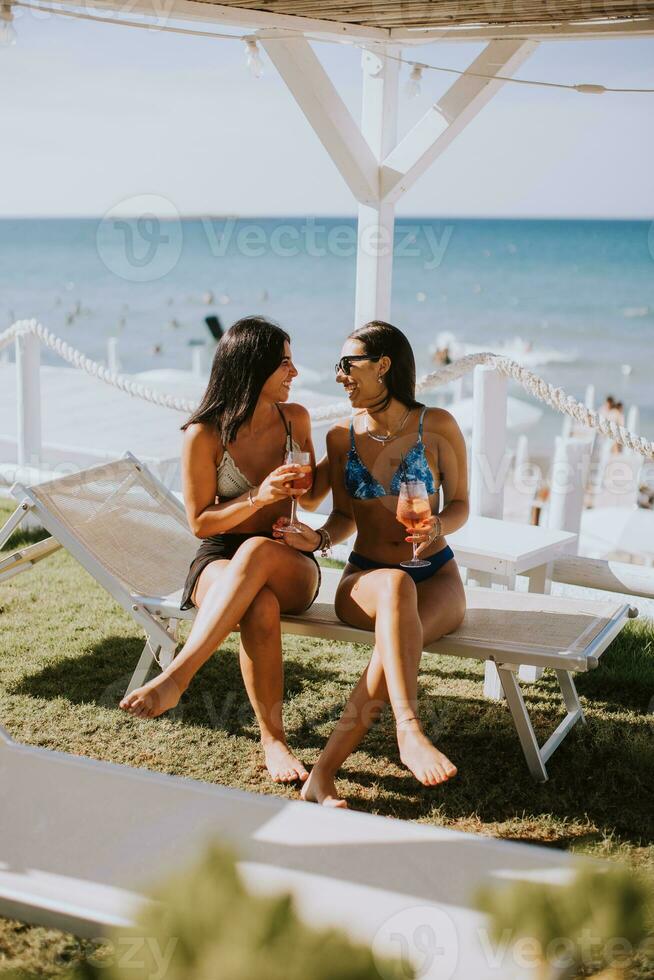 sorridente giovane donne nel bikini godendo vacanza su il spiaggia foto