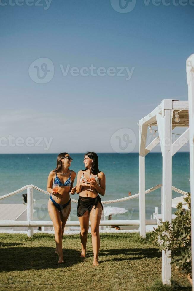 sorridente giovane donne nel bikini godendo vacanza su il spiaggia foto