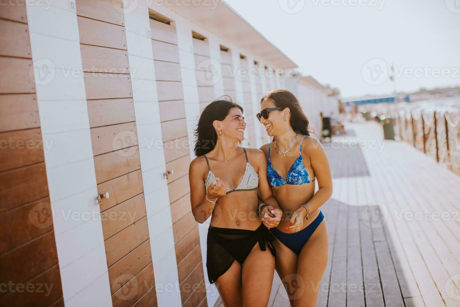 sorridente giovane donne nel bikini godendo vacanza su il spiaggia foto