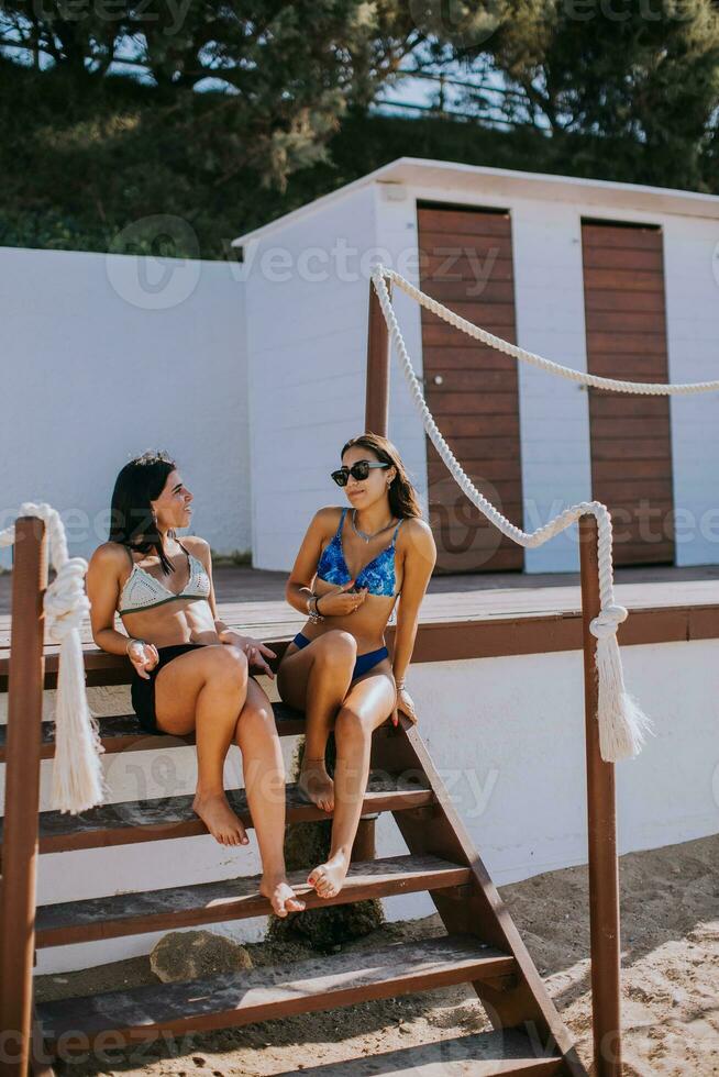 sorridente giovane donne nel bikini godendo vacanza su il spiaggia foto