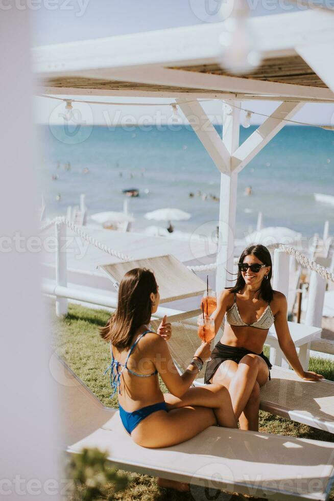 sorridente giovane donne nel bikini godendo vacanza su il spiaggia foto