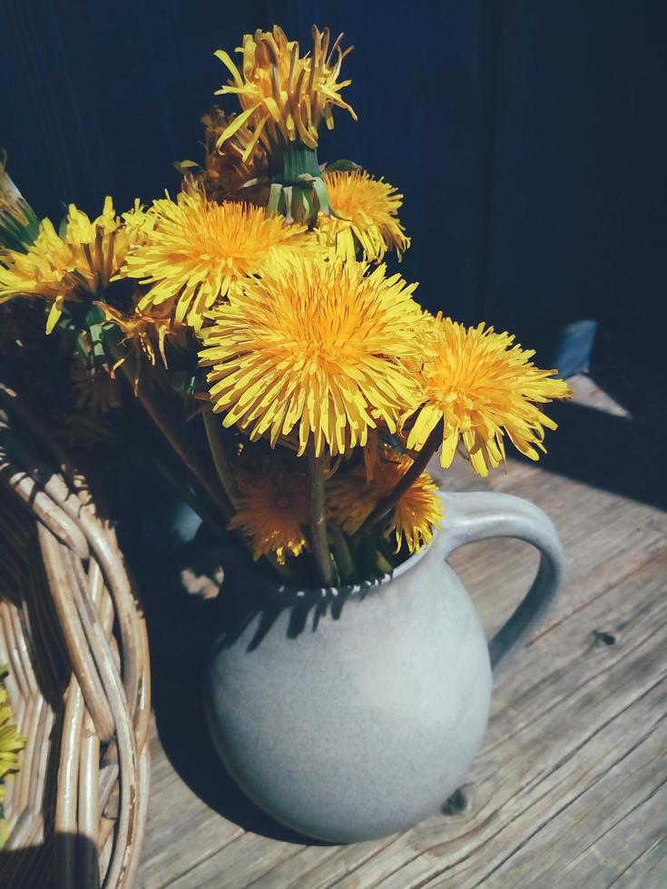 fiori estivi gialli in vaso su sfondo rustico blu foto