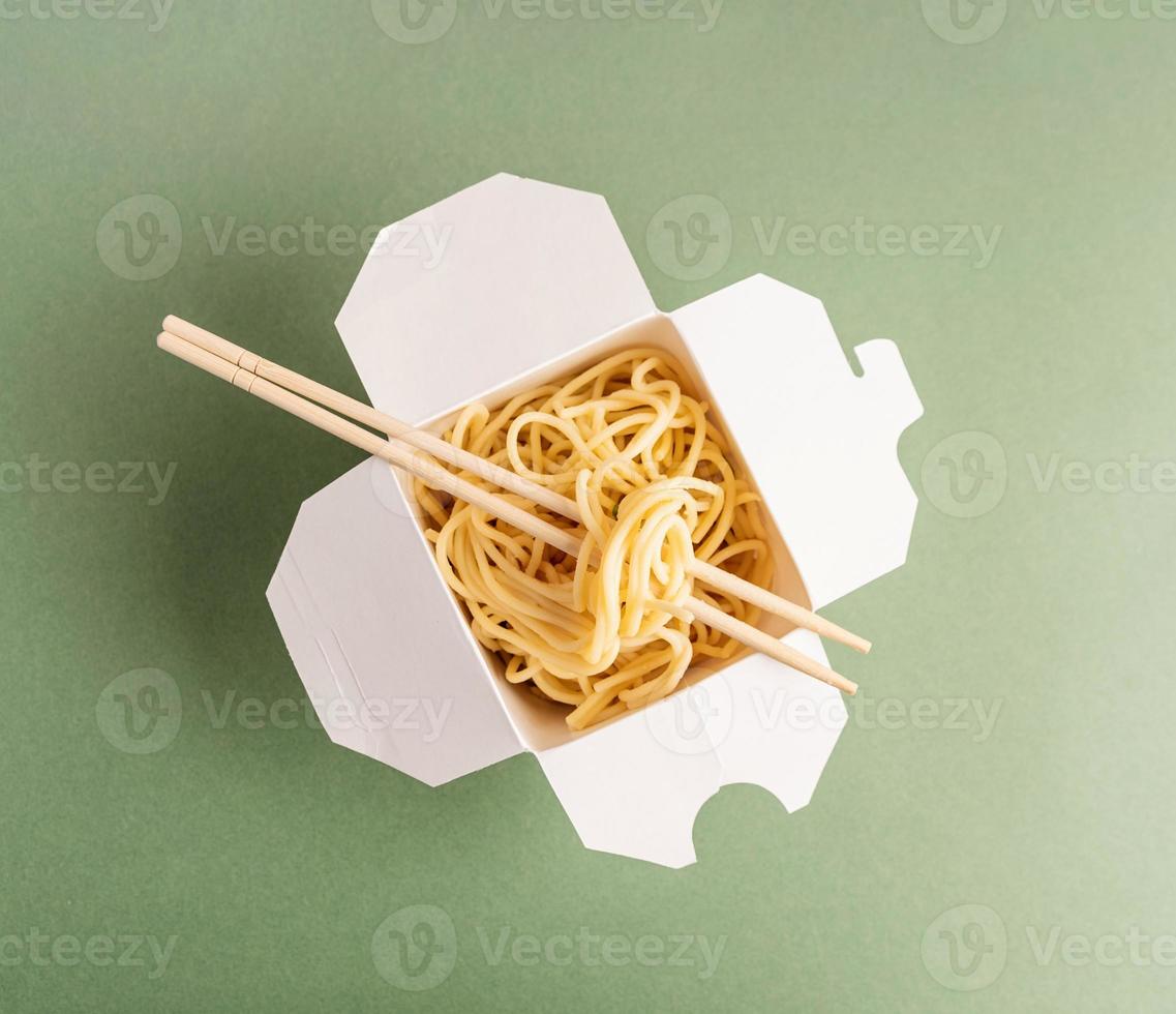 scatola di carta per wok aperta con noodles e bacchette foto