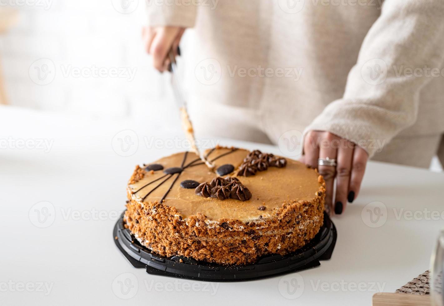 primo piano delle mani di una donna che tagliano una torta foto