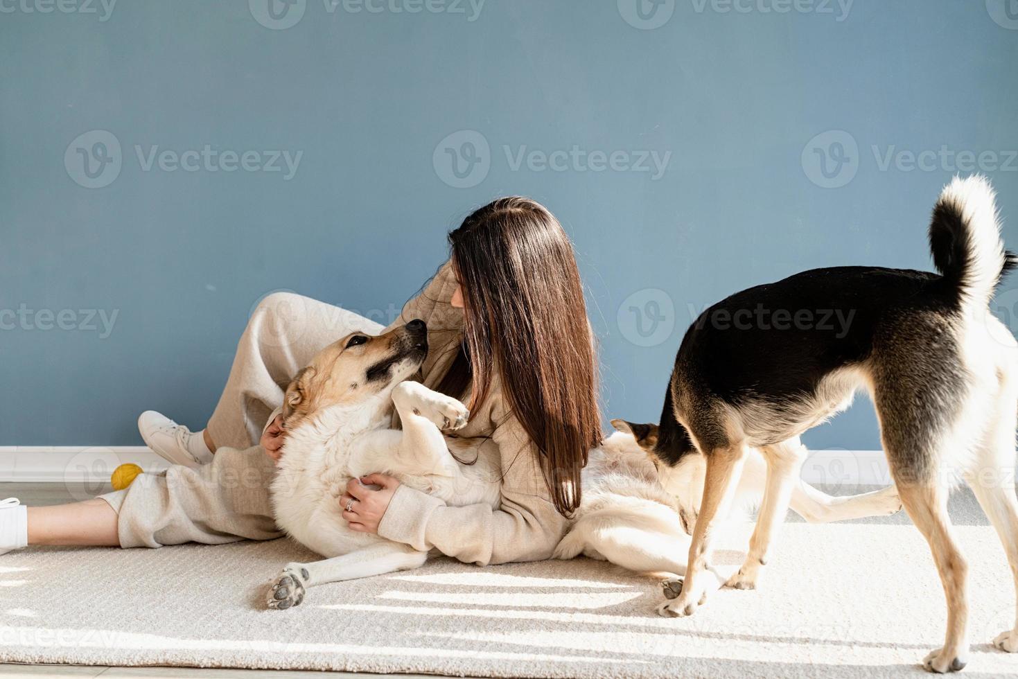 bella donna con cane giocoso che si abbraccia a casa foto