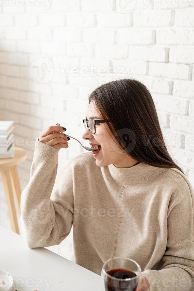 donna seduta al tavolo bianco, mangiando torta e bevendo caffè foto