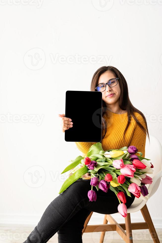 donna con bouquet di tulipani freschi e tavoletta digitale vuota foto