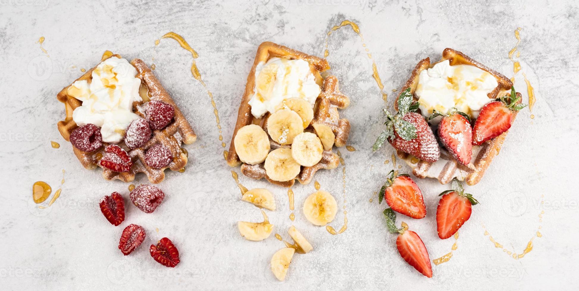 waffle con frutta e bacche, panna e miele in un piatto foto