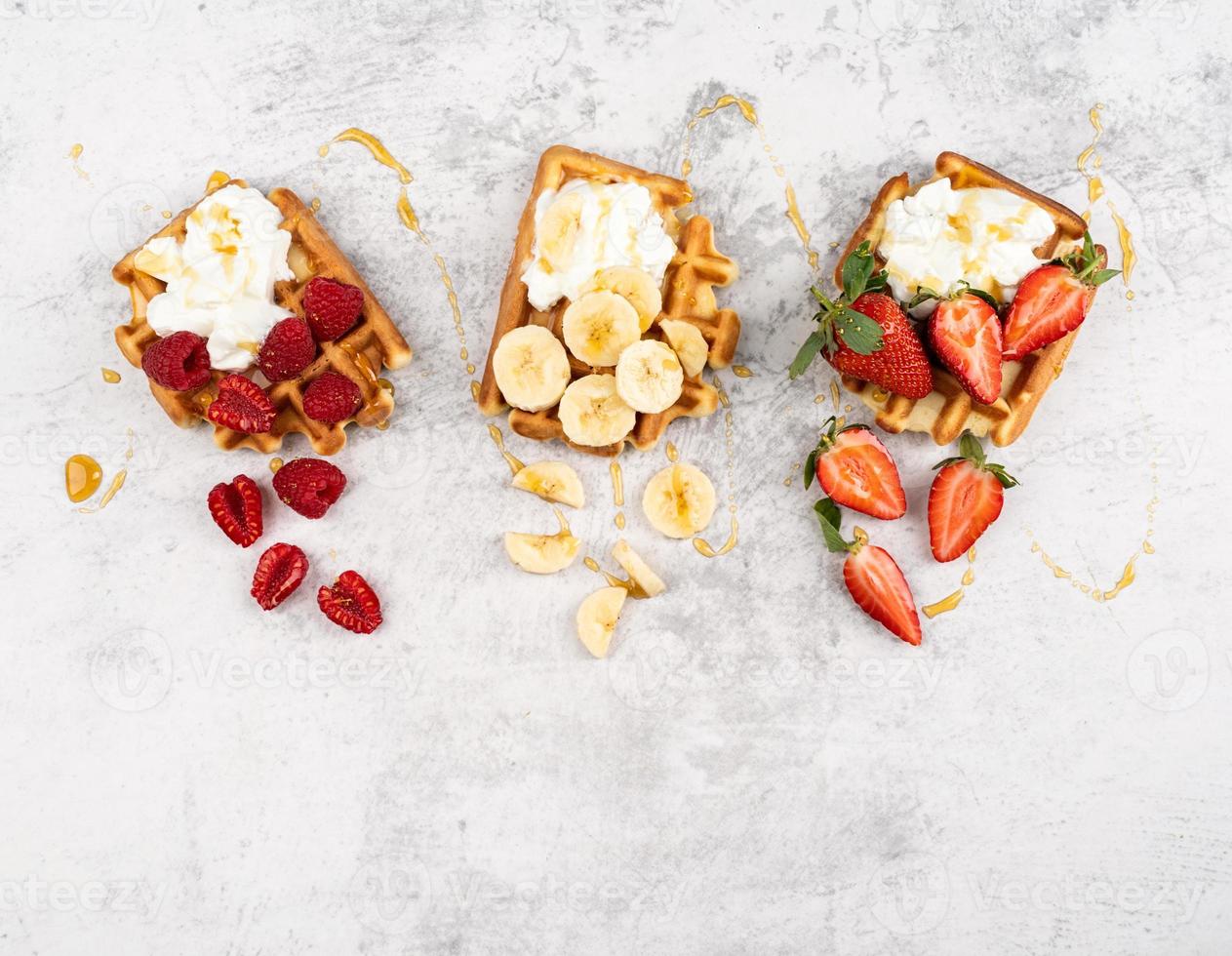 waffle con frutta e bacche, panna e miele in un piatto foto