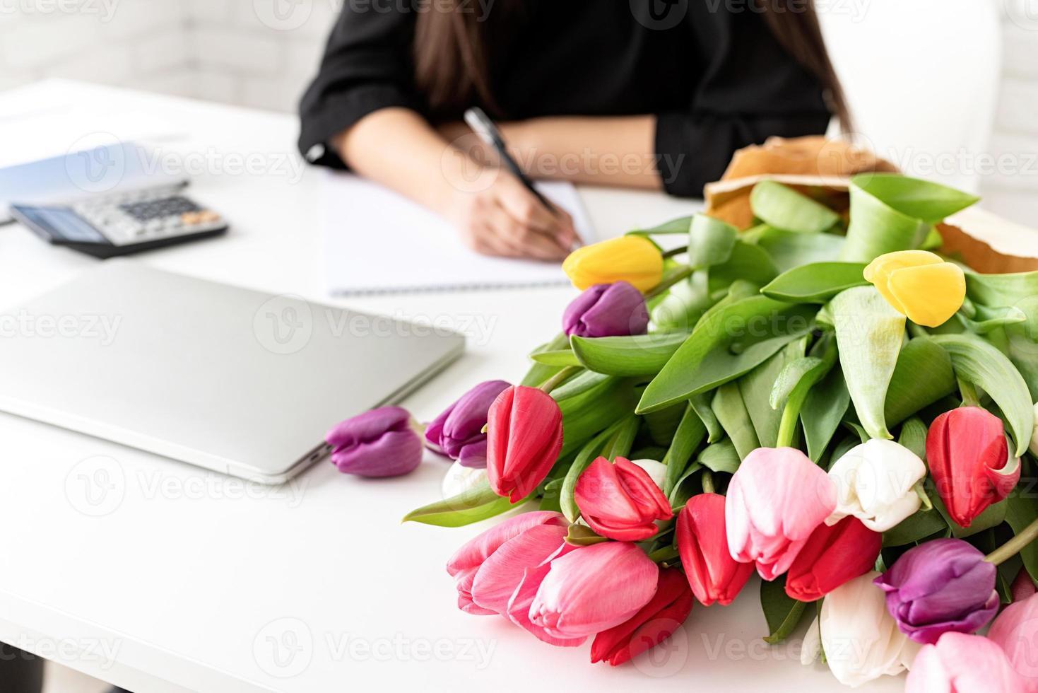 fiorista donna che scrive su un quaderno o un calendario in ufficio foto