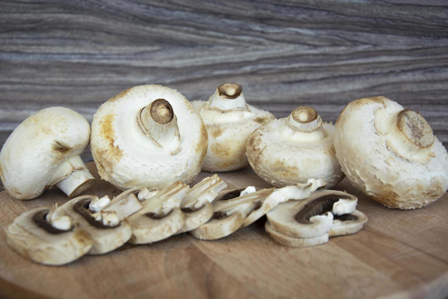 i funghi champignon giacciono su uno sfondo di legno foto