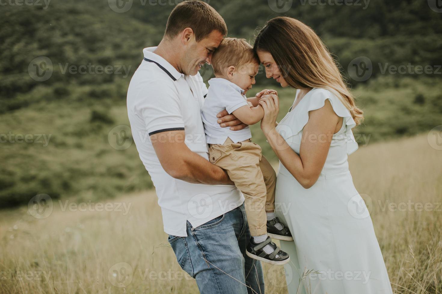 giovane famiglia con un ragazzino carino che si diverte all'aperto nel campo foto