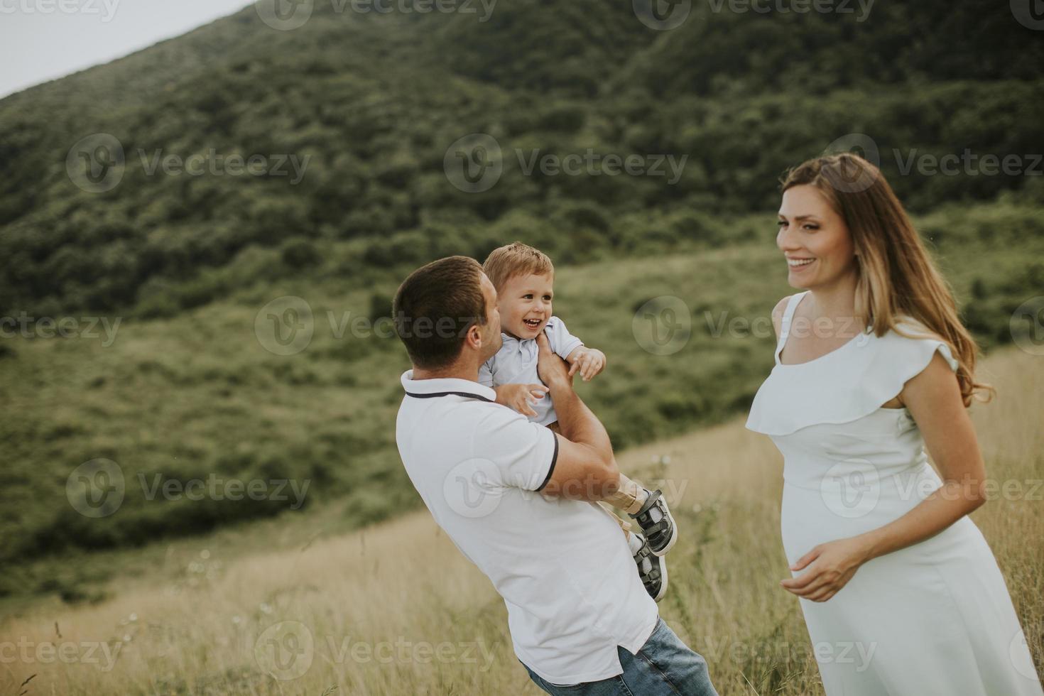 giovane famiglia con un ragazzino carino che si diverte all'aperto nel campo foto