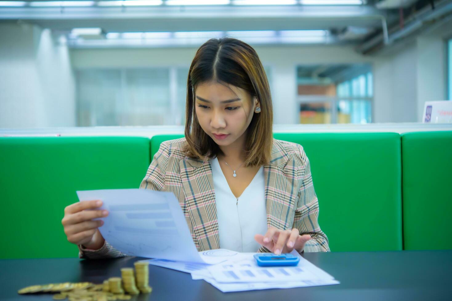 giovane bellissimo asiatico attività commerciale donna è controllo finanziario documenti con un' grave espressione, digitale marketing. foto