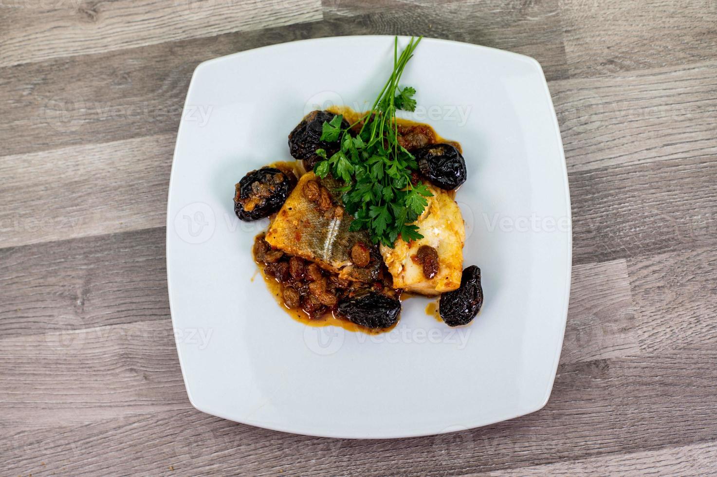 piatto di baccalà in agrodolce su piatto bianco foto