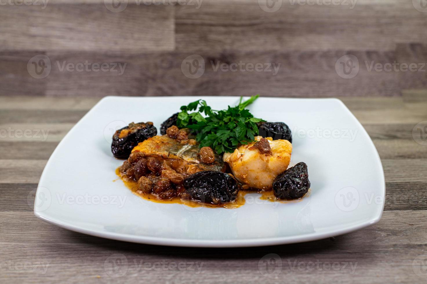 piatto di baccalà in agrodolce su piatto bianco foto