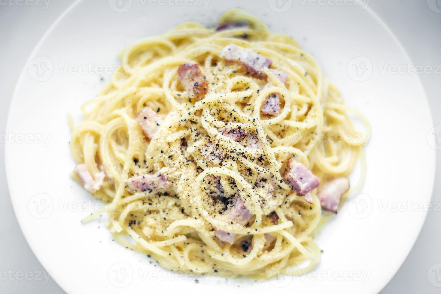 spaghetti pasta alla carbonara con pancetta crema di prosciutto e piatto di peperoni kampot foto