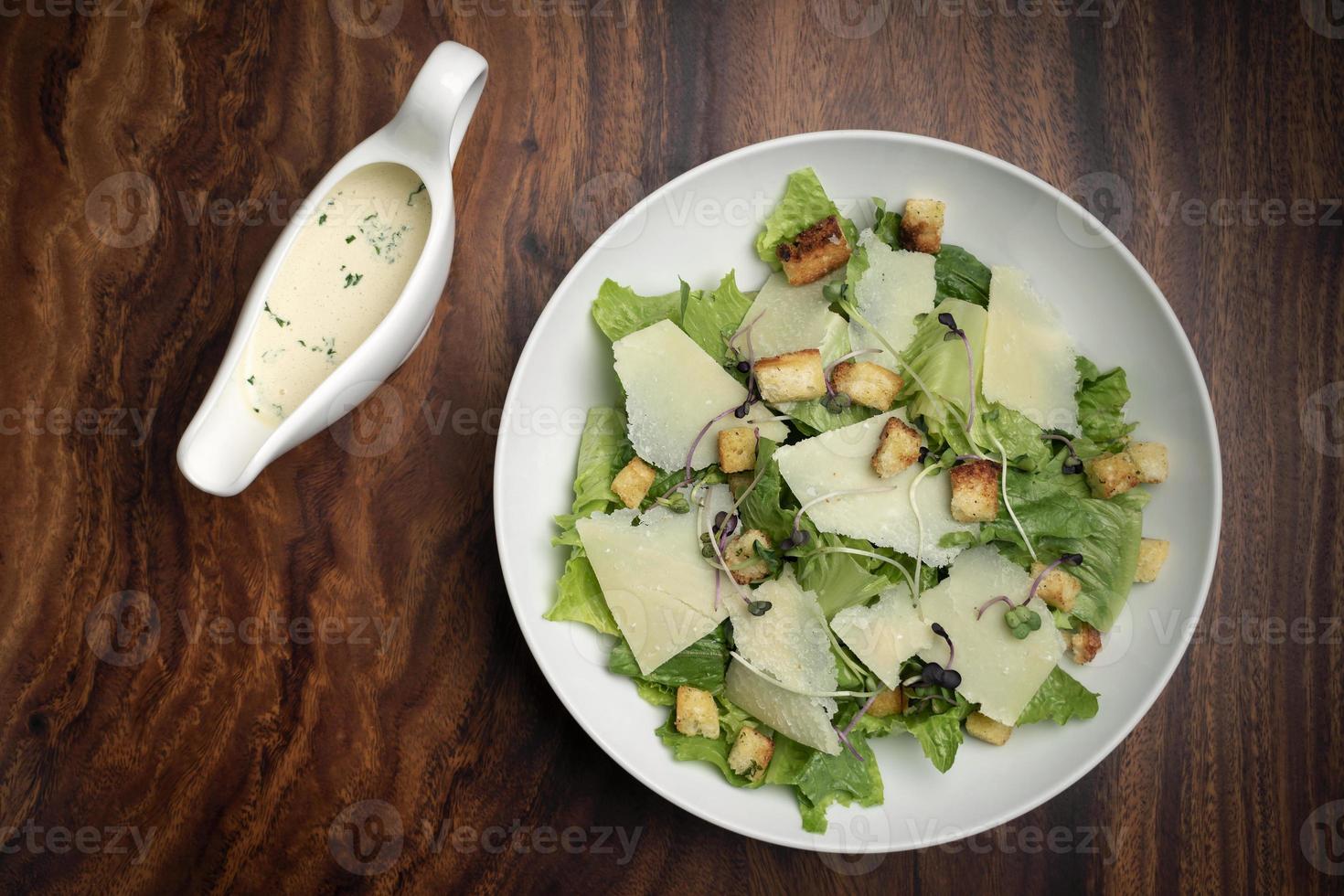 caesar salad con parmigiano e crostini su tavola di legno foto