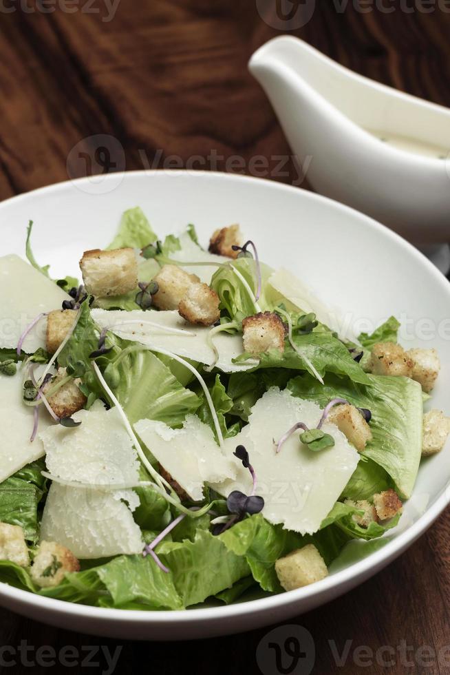 caesar salad con parmigiano e crostini su tavola di legno foto