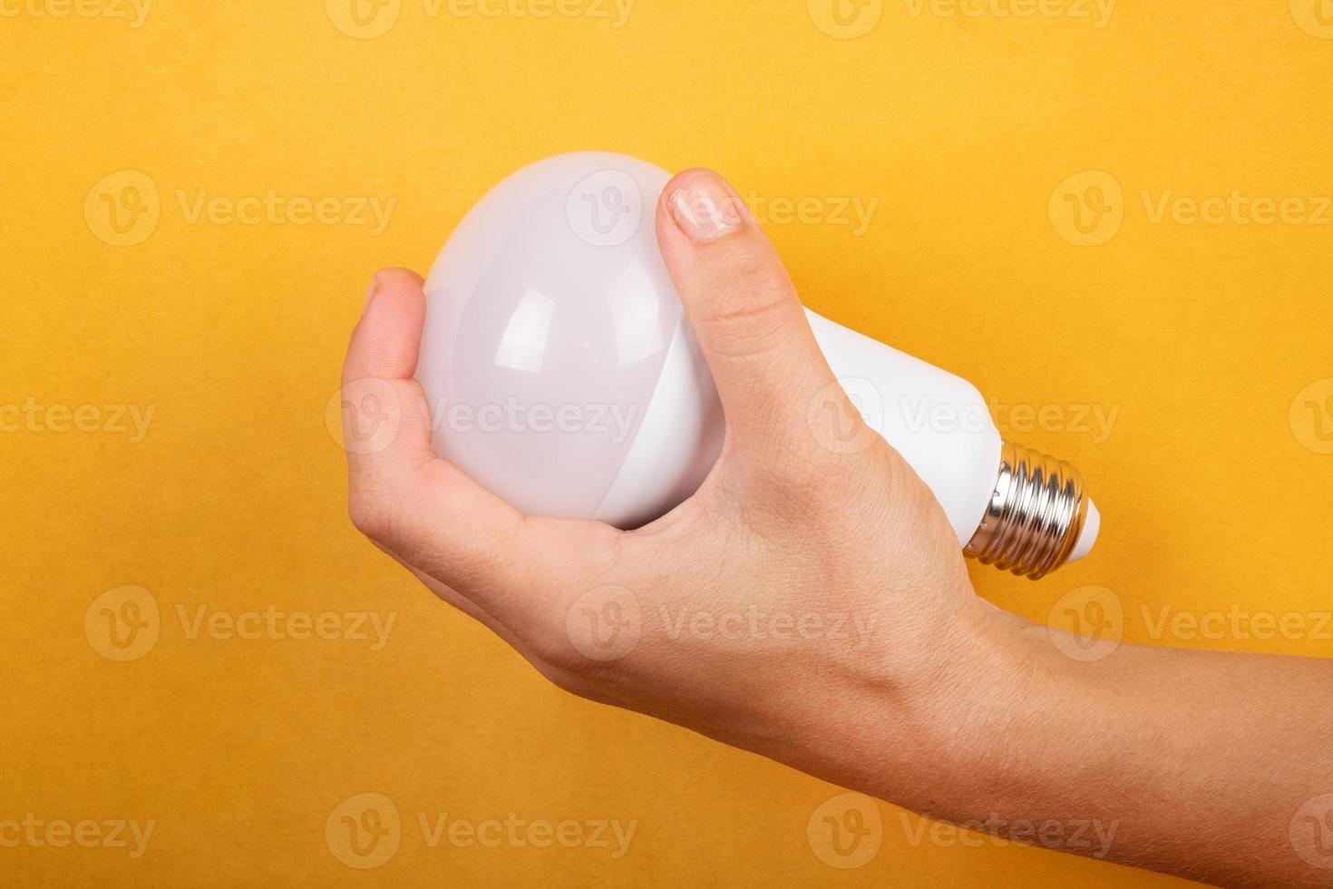 concetto di risparmio energetico, lampada a risparmio led in mano su sfondo giallo. foto