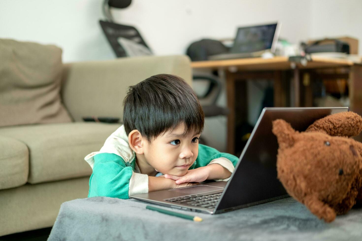 asiatico ragazzo studiando in linea e fare attività su il computer portatile foto