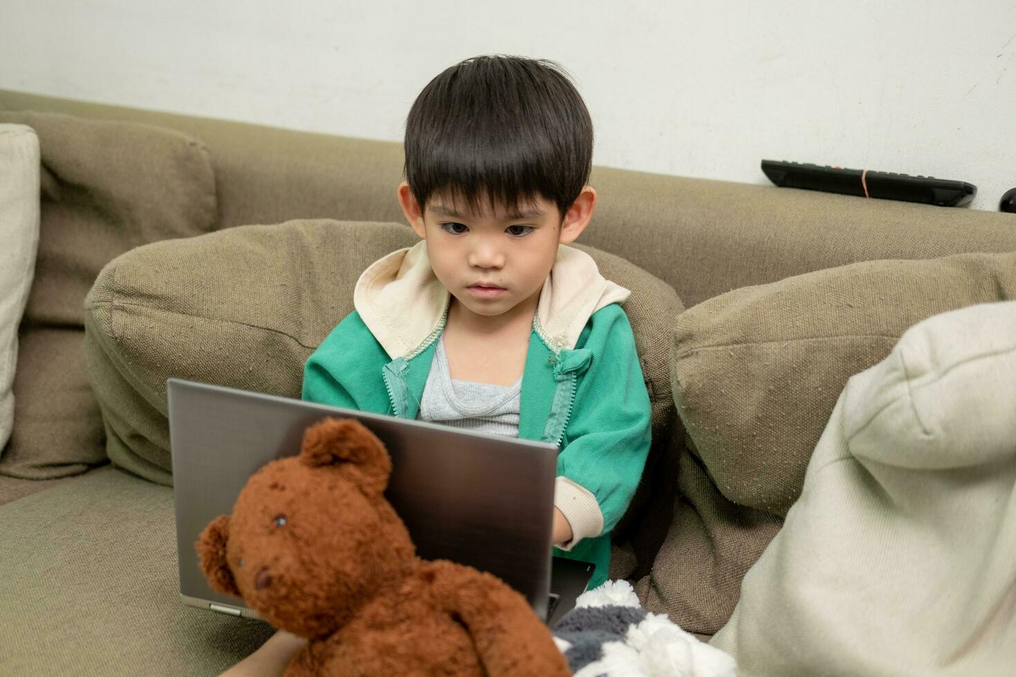 asiatico ragazzo studiando in linea e fare attività su il computer portatile foto