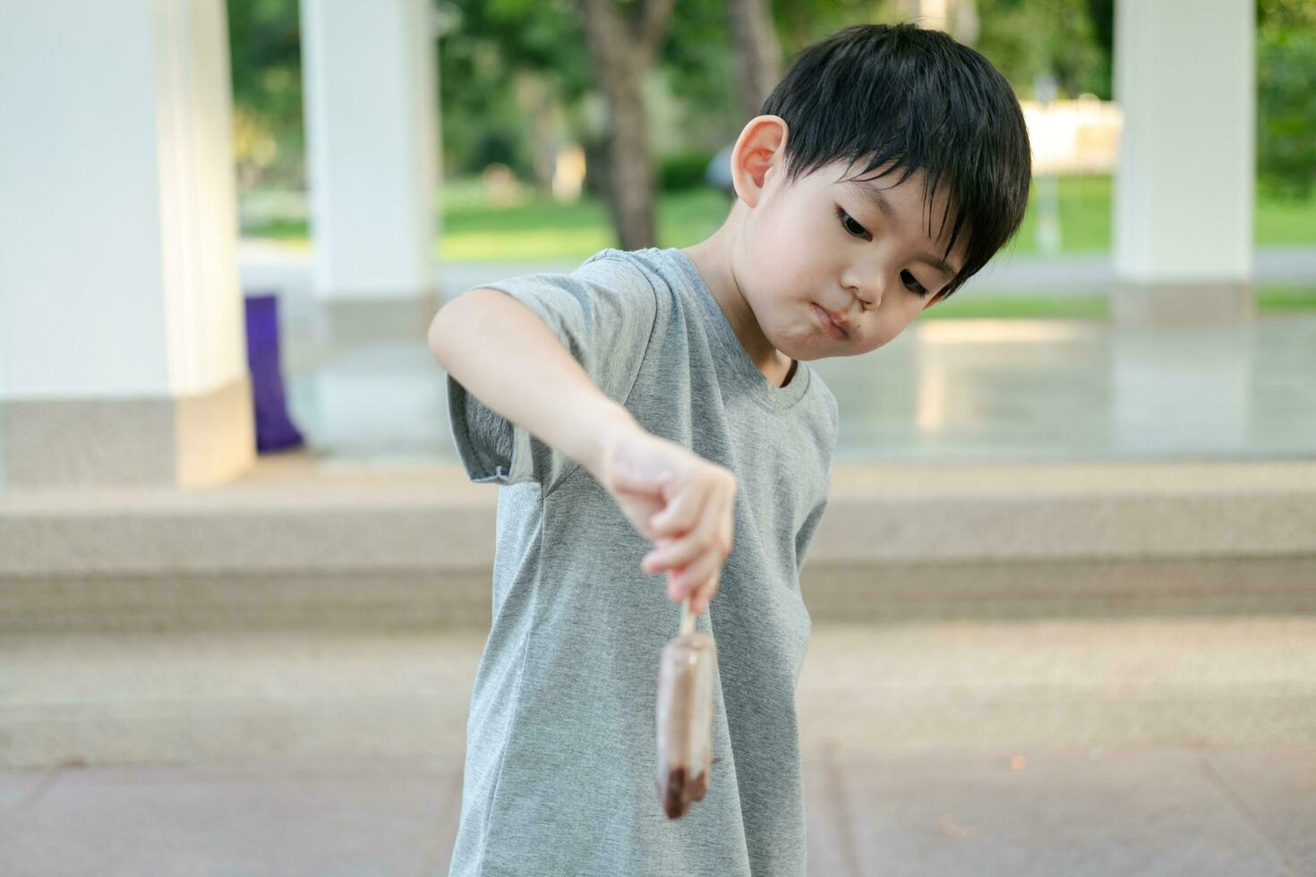 il viso di un asiatico ragazzo in piedi e mangiare ghiaccio crema. foto