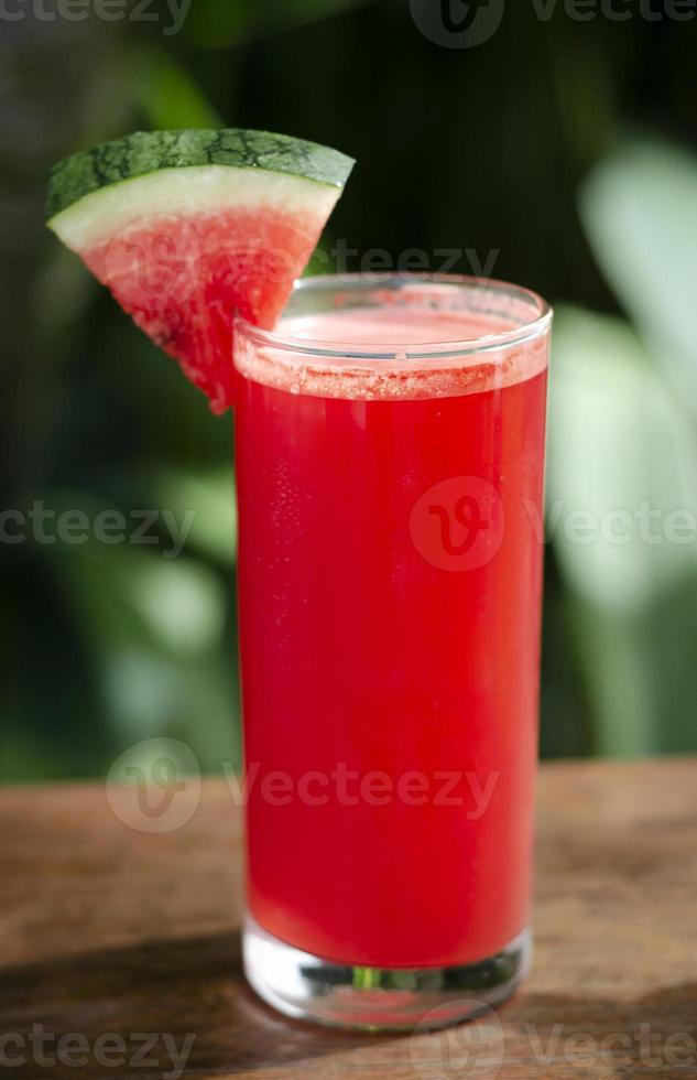 bicchiere di succo di cocomero biologico fresco sul tavolo da giardino all'aperto in una giornata di sole foto