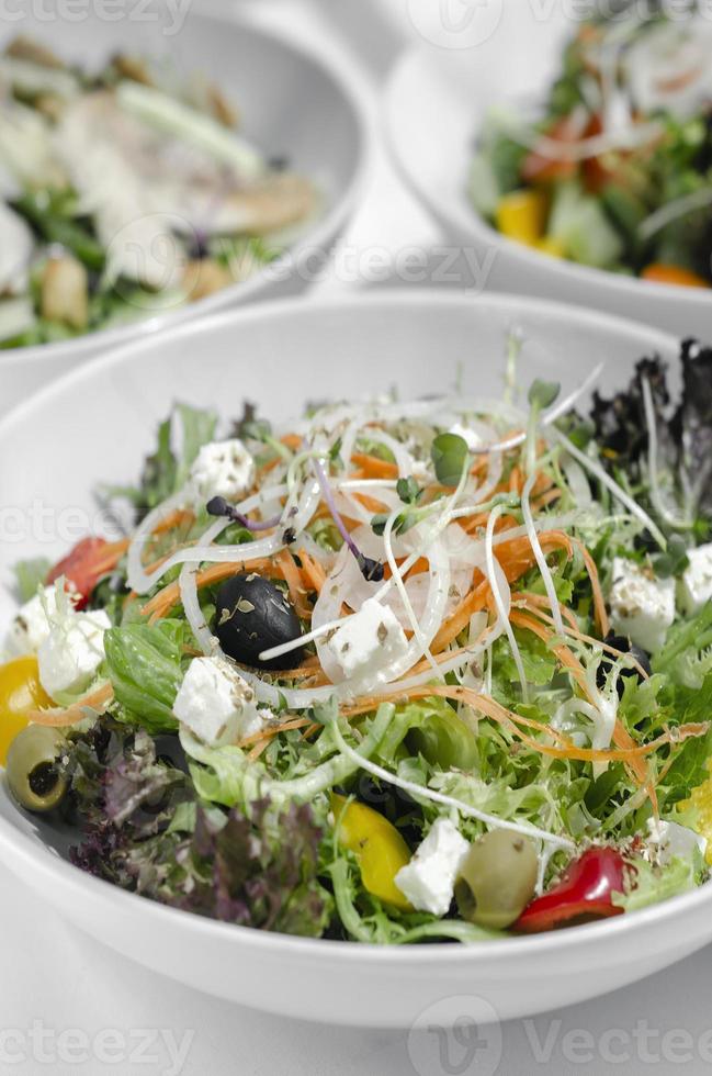 Insalate organiche fresche miste in ciotole sul tavolo bianco del ristorante foto