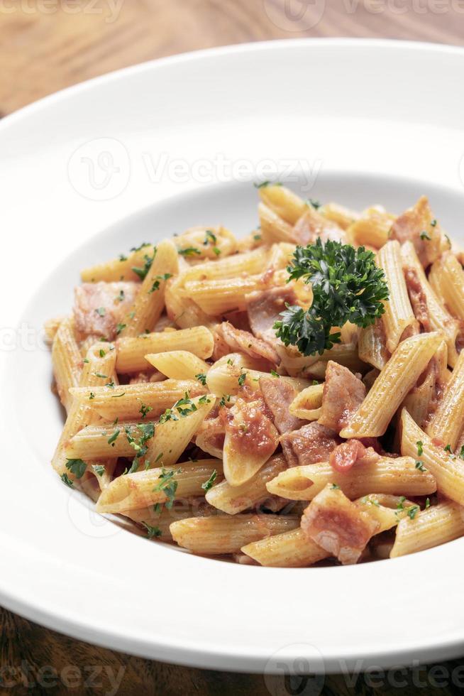 penne amatriciana pomodoro e prosciutto pasta al sugo su tavola di legno sfondo foto