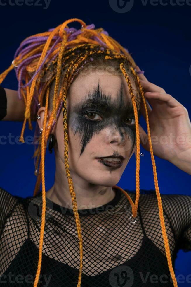 informale giovane donna con colorato dreadlocks acconciatura, orrore nero palcoscenico rendere su dipinto su viso foto