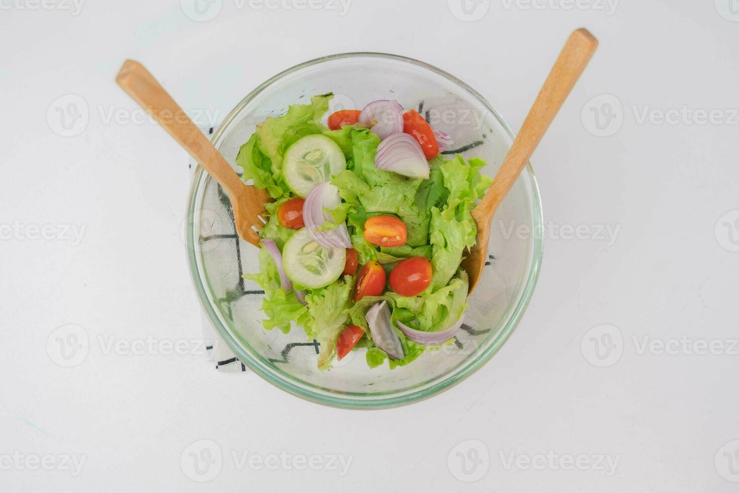 cucinando - donna fabbricazione fresco biologico verdura insalata nel il cucina. femmina mani preparazione delizioso salutare cibo a casa, miscelazione verdure nel un' ciotola, avvicinamento. foto